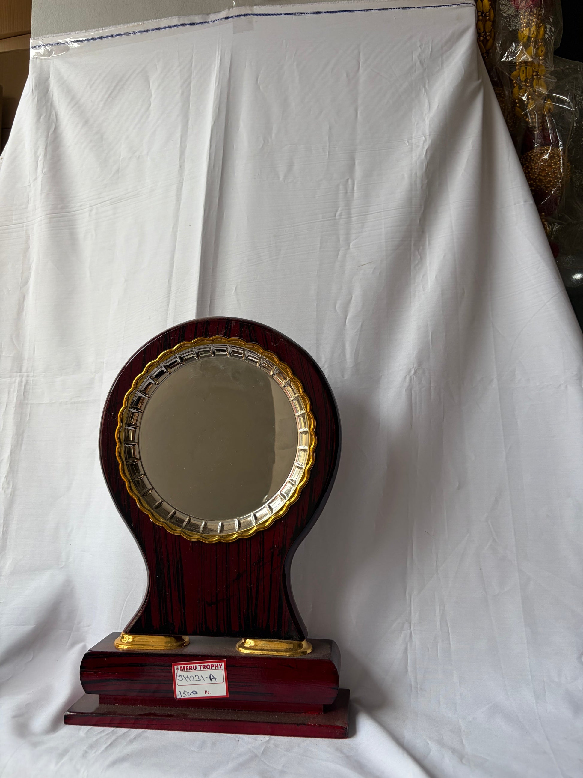 JH 231 A dark wood circular decorative plaques featuring a gold metal trim and a polished pedestal base for formal awards.